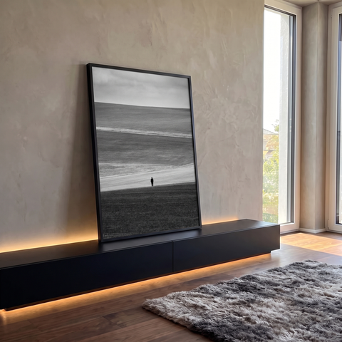 Figura solitária em campo ondulado sob céu nublado em fotografia preto e branco, quadro decorativo