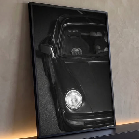 Porsche clássico preto e branco à noite com farol aceso e dachshund espiando no banco, quadro decorativo