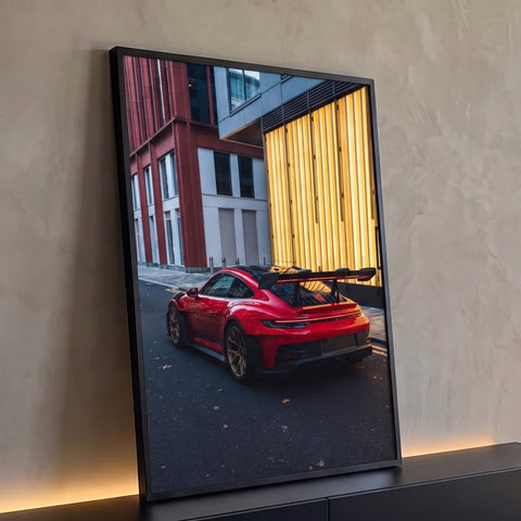 Porsche GT3 RS vermelho visto de trás em rua da cidade com fachada dourada iluminada, quadro decorativo