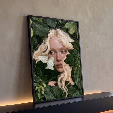 Mulher loira com sardas entre folhas verdes e mariposa branca no rosto, quadro decorativo