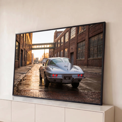 Corvette Stingray prata visto de trás em rua de tijolos molhada entre fábricas antigas, quadro decorativo