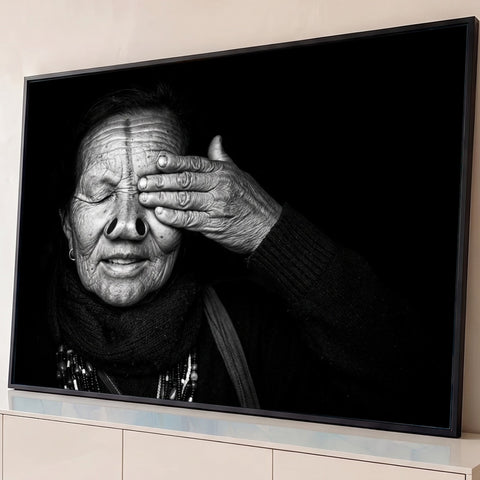 Retrato em preto e branco de mulher idosa tribal cobrindo o olho com a mão, fundo preto, quadro decorativo
