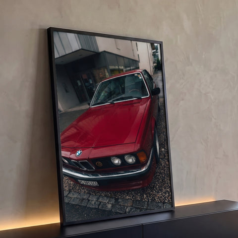 BMW clássica vermelha com gotas de chuva no capô, faróis redondos e calçada de pedras, quadro decorativo