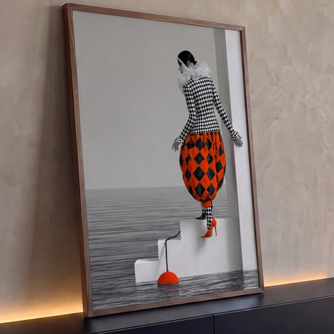 Arlequim em xadrez preto e branco e calça laranja descendo escada branca sobre o mar, quadro decorativo