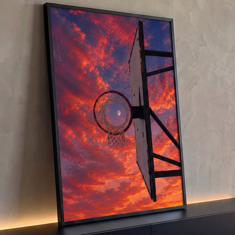 Aro de basquete com rede emoldurando a lua sob céu de pôr do sol laranja e vermelho, quadro decorativo