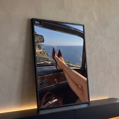 Pernas de mulher com scarpin vinho no painel de conversível vintage com vista para o mar, quadro decorativo