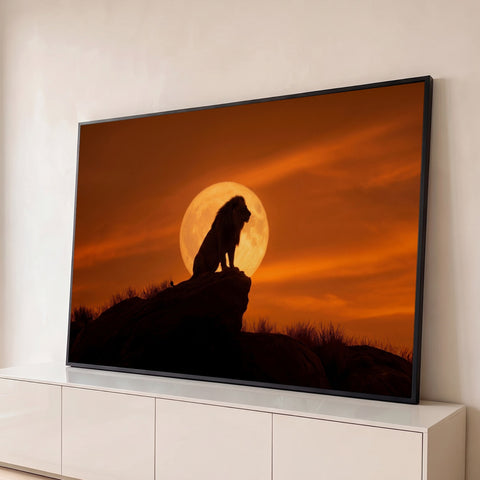 Leão em silhueta sentado sobre rocha diante da lua cheia em céu laranja de entardecer, quadro decorativo