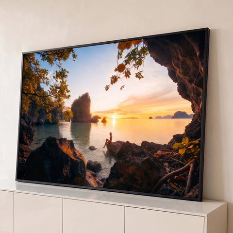 Pôr do sol dourado visto de gruta, mulher sentada na rocha, mar calmo e ilhas tropicais, quadro decorativo