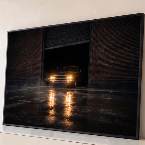 Muscle car antigo com faróis acesos saindo de galpão de tijolos à noite, reflexo no chão molhado, quadro decorativo