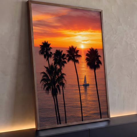 Pôr do sol laranja no mar com palmeiras altas em silhueta e veleiro branco ao centro, quadro decorativo