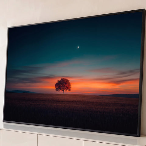 Árvore solitária em campo ao pôr do sol laranja, céu azul-petróleo e lua crescente, quadro decorativo