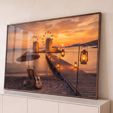Pôr do sol laranja com moinhos no mar, píer com lanternas e violão na areia, quadro decorativo