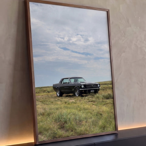 Mustang clássico preto estacionado em campo de grama sob céu nublado, quadro decorativo