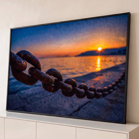 Corrente de ferro enferrujada em cais com pôr do sol laranja refletido no mar, quadro decorativo