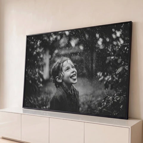 Fotografia preto e branco de menino sorrindo com a língua de fora sob a chuva no jardim, quadro decorativo