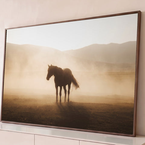 Cavalo solitário em contraluz na poeira dourada do campo com montanhas ao fundo, quadro decorativo