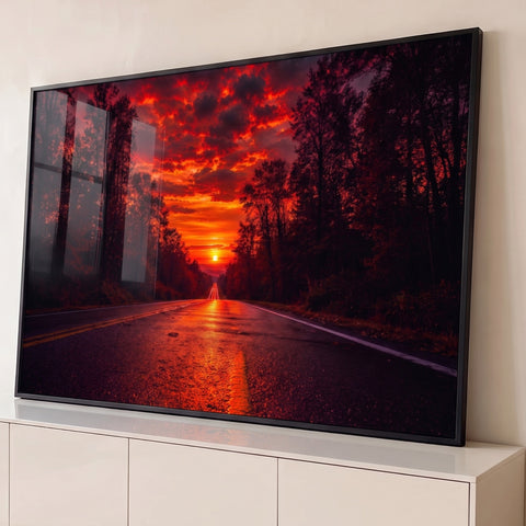 Estrada molhada entre árvores rumo ao sol no horizonte sob céu vermelho em chamas, quadro decorativo