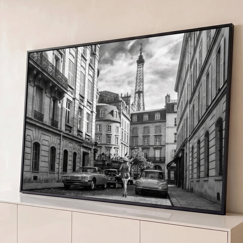 Rua de Paris em preto e branco com carros antigos, mulher caminhando e a Torre Eiffel ao fundo, quadro decorativo