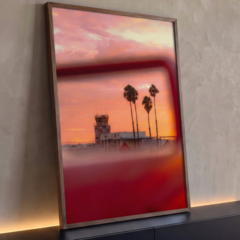 Palmeiras e torre de aeroporto sob pôr do sol rosa e laranja vistas no retrovisor vermelho, quadro decorativo