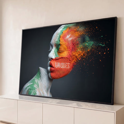 Rosto de mulher pintado de laranja, verde e branco se desfazendo em pó sobre fundo cinza, quadro decorativo