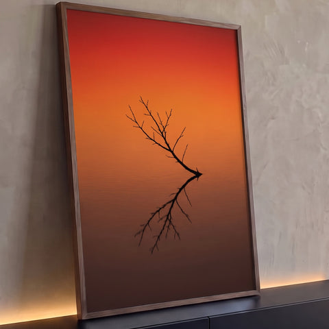 Galho seco em silhueta refletido na água parada sob céu vermelho e laranja do pôr do sol, quadro decorativo