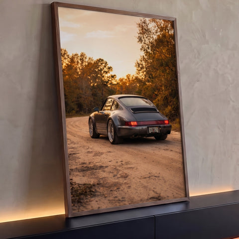 Porsche 911 cinza de traseira em estrada de terra com árvores de outono ao pôr do sol, quadro decorativo