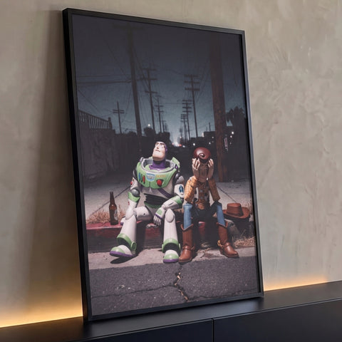 Bonecos de caubói e astronauta sentados no meio-fio de rua noturna com postes, quadro decorativo