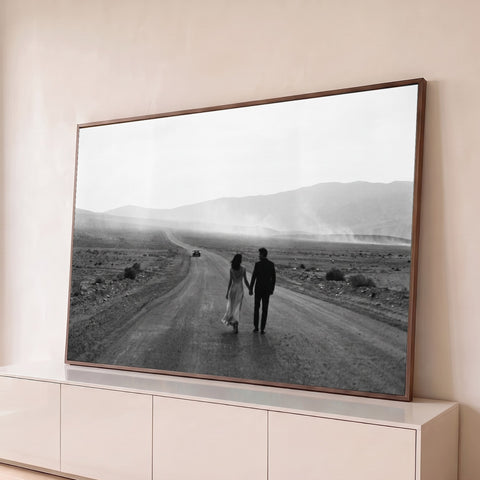 Casal de mãos dadas caminhando em estrada deserta entre montanhas, foto preto e branco, quadro decorativo