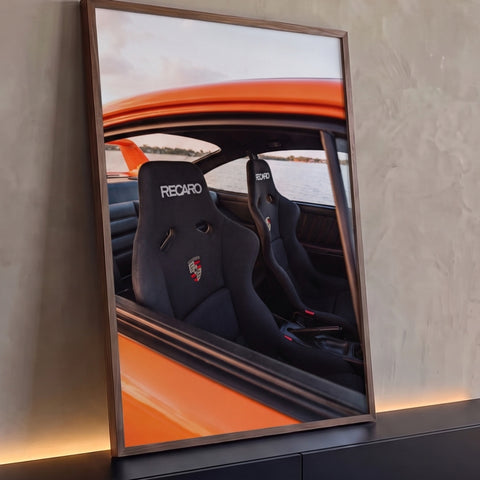 Interior de Porsche laranja com bancos esportivos Recaro pretos e lago ao fundo, quadro decorativo