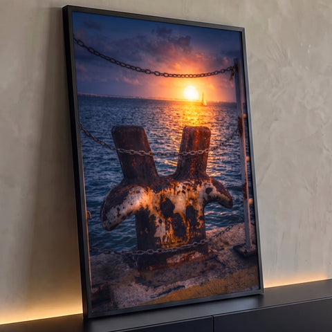 Cabeço de amarração enferrujado no cais com pôr do sol no mar e veleiro ao fundo, quadro decorativo