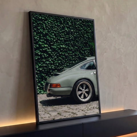 Porsche 911 clássico verde-sálvia visto de traseira, muro de hera e piso de paralelepípedo, quadro decorativo