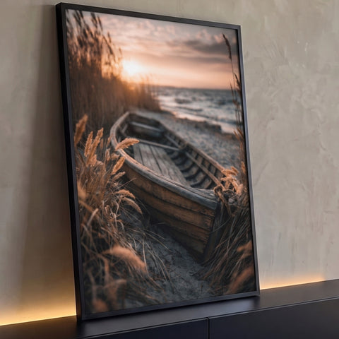 Barco de madeira antigo na areia entre gramíneas douradas com mar e pôr do sol ao fundo, quadro decorativo