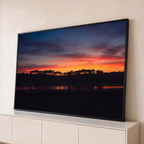 Pôr do sol laranja e azul no crepúsculo, silhueta de pinheiros refletida na água da maré, quadro decorativo