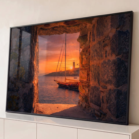 Veleiro ancorado ao pôr do sol laranja com farol, visto por janela de muralha de pedra, quadro decorativo