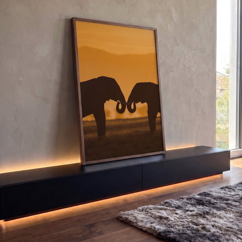 Silhueta de dois elefantes unindo as trombas ao pôr do sol laranja na savana africana, quadro decorativo