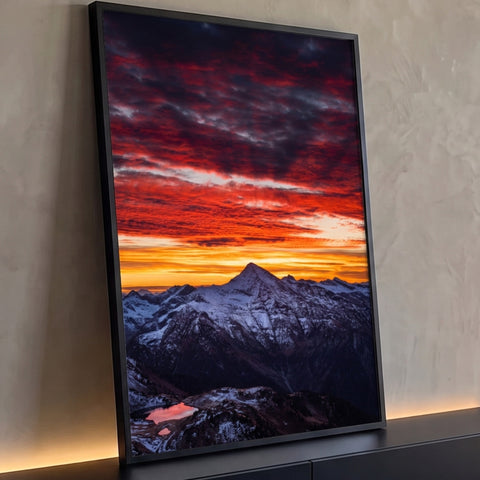 Pico nevado sob céu de nuvens vermelhas ao pôr do sol com pequeno lago refletindo, quadro decorativo