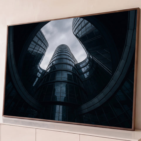 Prédios de vidro curvos em espiral vistos de baixo sob céu nublado, em tons azul-escuros, quadro decorativo