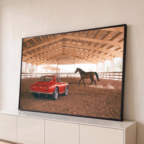 Ferrari vermelha vintage e cavalo marrom correndo em picadeiro coberto com chão de terra, quadro decorativo