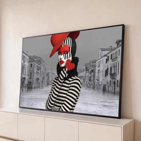 Mulher com maquiagem de pierrô, chapéu vermelho e coração diante de canal de Veneza cinza, quadro decorativo