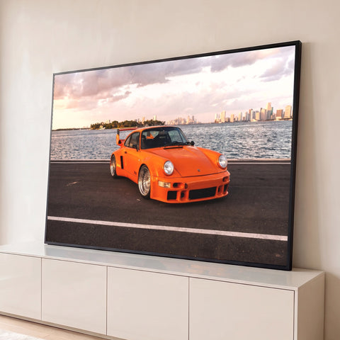 Porsche 911 clássico laranja à beira-mar com o skyline de Miami ao entardecer, quadro decorativo