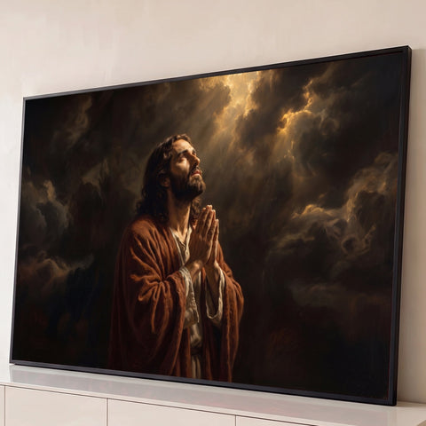 Jesus Cristo de manto marrom orando de mãos unidas sob raios de luz entre nuvens escuras, quadro decorativo