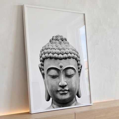 Cabeça de Buda esculpida em pedra com olhos fechados sobre fundo branco em preto e branco, quadro decorativo