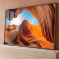 Cânion de arenito laranja com ondas de rocha, sol radiante e céu azul, quadro decorativo