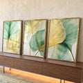 Trio de folhas translúcidas verdes e douradas sobre fundo claro, estilo botânico, quadro decorativo