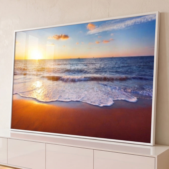 Praia ao pôr do sol com ondas de espuma branca, areia laranja e céu azul com nuvens, quadro decorativo
