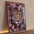 Rosto de onça pintada com olhos azuis cercado por flores rosas e folhas verdes, quadro decorativo