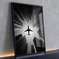 Avião em silhueta visto de baixo entre arranha-céus em preto e branco, quadro decorativo