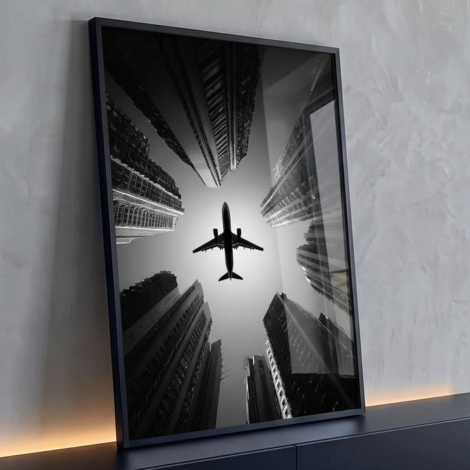 Avião em silhueta visto de baixo entre arranha-céus em preto e branco, quadro decorativo