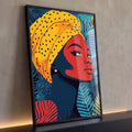Mulher negra de perfil com turbante amarelo de bolinhas e folhas tropicais azuis, quadro decorativo