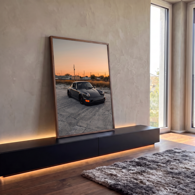 Porsche 911 preto rebaixado em pátio de concreto sob céu laranja de pôr do sol, quadro decorativo